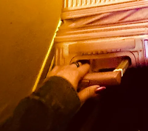 A hand at a brass letterbox in warm evening light