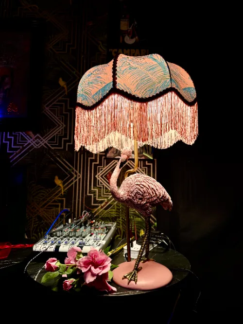 A flamingo lamp with a fringed shade beside the mixing desk